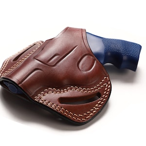 May include: A brown leather holster with a stitched design and a blue handgun inside.