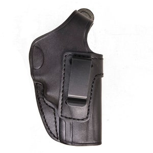 May include: A black leather holster with a metal clip. The holster is designed to be worn on the inside of the waistband. The stitching is visible along the edges of the holster.
