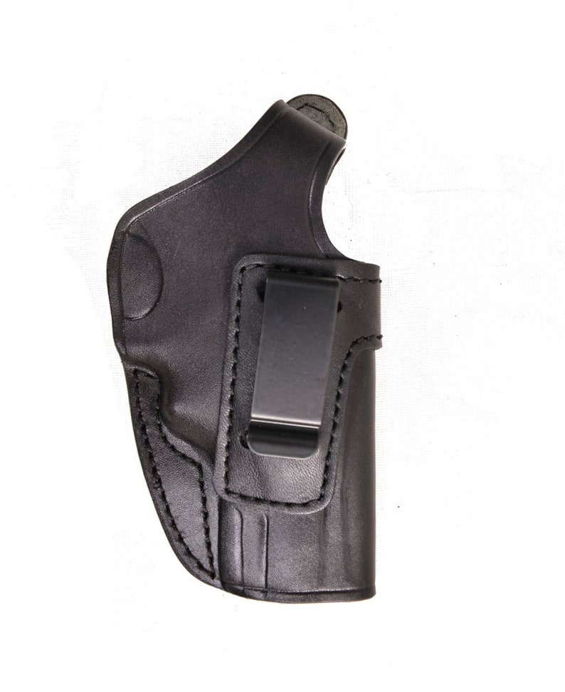 May include: A black leather holster with a metal clip. The holster is designed to be worn on the inside of the waistband. The stitching is visible along the edges of the holster.