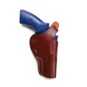 May include: A blue handgun in a brown leather holster. The holster has white stitching detail.