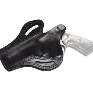 May include: A black leather holster for a revolver. The holster has a belt loop and a snap closure. The revolver is silver and has a wooden handle.