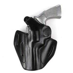 May include: A black leather holster with a silver revolver. The holster is designed to securely hold the firearm. The image is set against a white background.