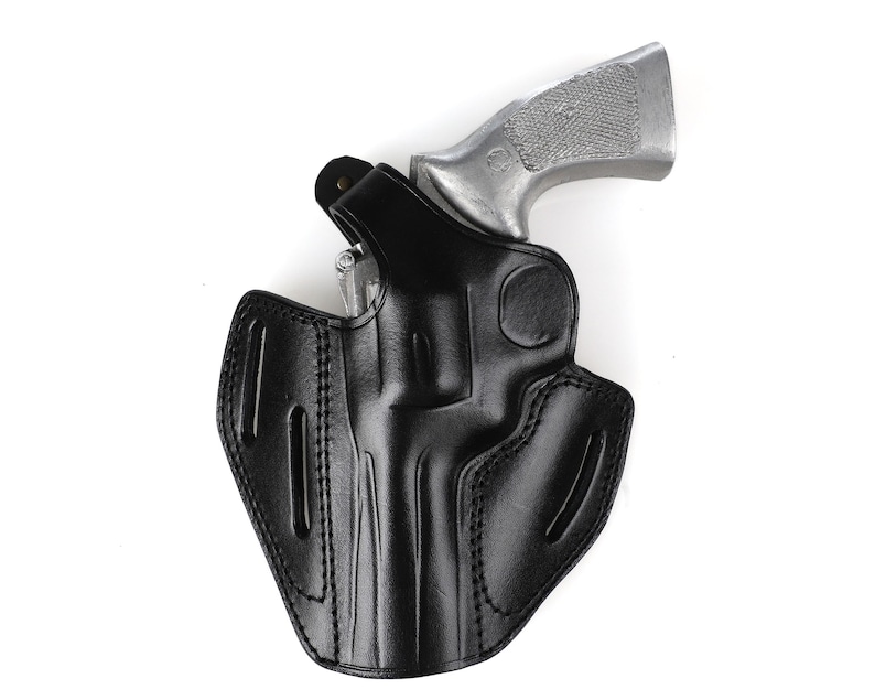 May include: A black leather holster with a silver revolver. The holster is designed to securely hold the firearm. The image is set against a white background.