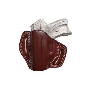 May include: A brown leather holster with white stitching and a silver handgun. The holster has a molded design and open slots for a belt. The handgun is partially visible, resting inside the holster.