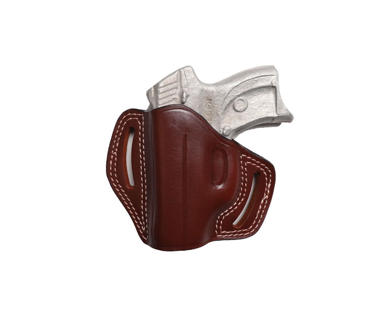 May include: A brown leather holster with white stitching and a silver handgun. The holster has a molded design and open slots for a belt. The handgun is partially visible, resting inside the holster.