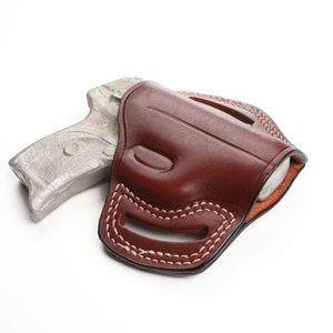 May include: A brown leather holster with white stitching, holding a silver-colored handgun. The holster has a molded design and is set against a white background. The stitching is visible along the edges and around the belt loops.