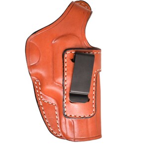 May include: A brown leather holster with white stitching and a black metal clip. The holster is designed to be worn on the body and is made of a durable material.