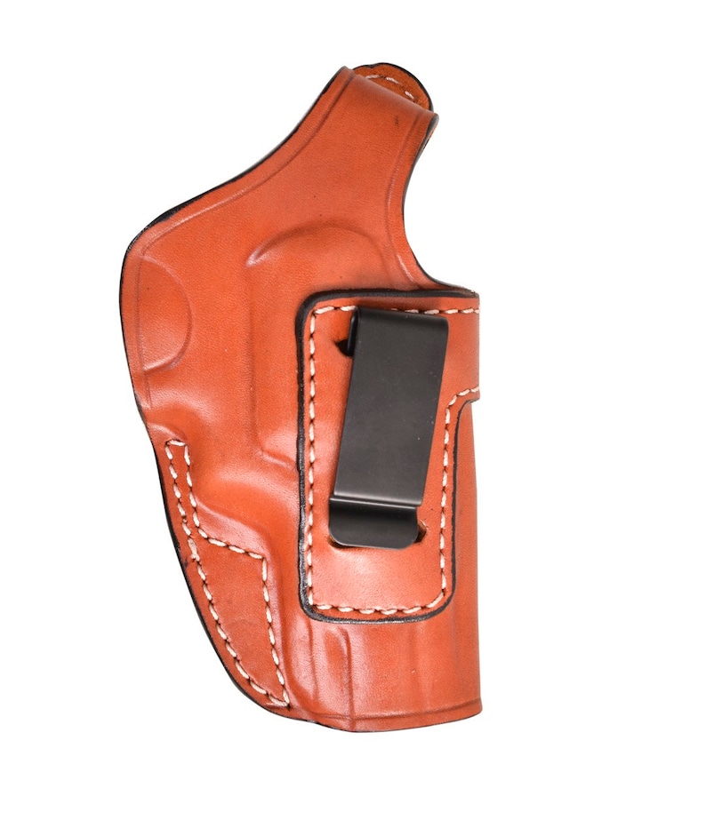 May include: A brown leather holster with white stitching and a black metal clip. The holster is designed to be worn on the body and is made of a durable material.