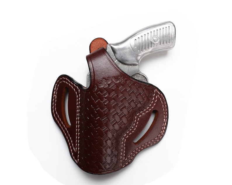 May include: A brown leather holster with a woven pattern and white stitching. The holster is designed to hold a small silver handgun.