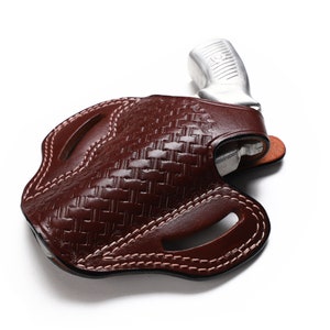 May include: A brown leather holster with a woven pattern and a silver handgun inside.
