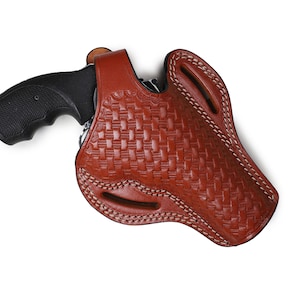 May include: A brown leather holster with a woven pattern and white stitching. A black handgun is inside the holster.