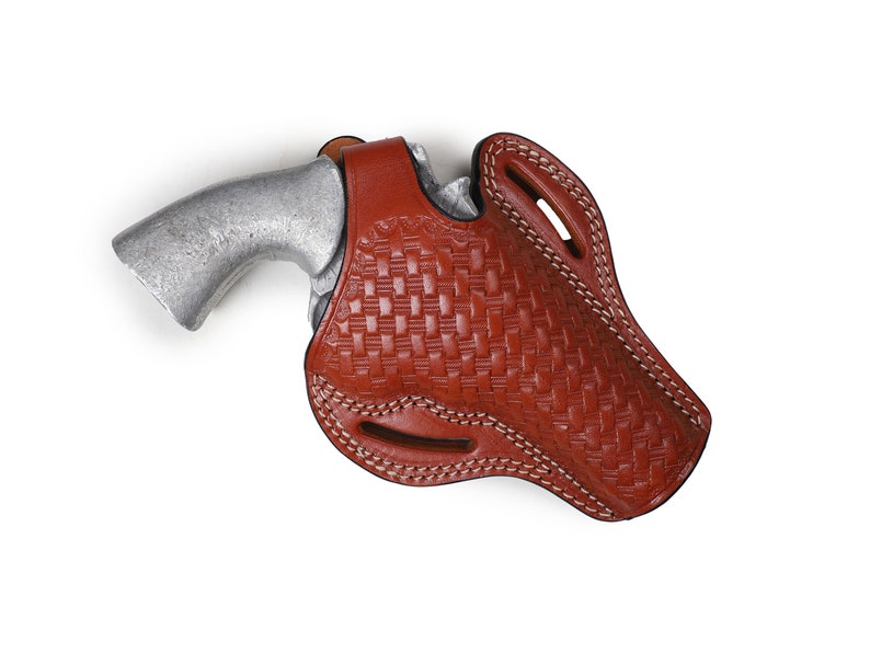 May include: A brown leather holster with a woven pattern and white stitching. A silver handgun is inside the holster.