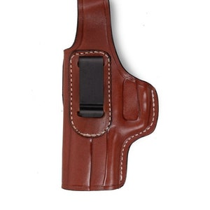 May include: A brown leather holster with a white stitch detail and a black clip.