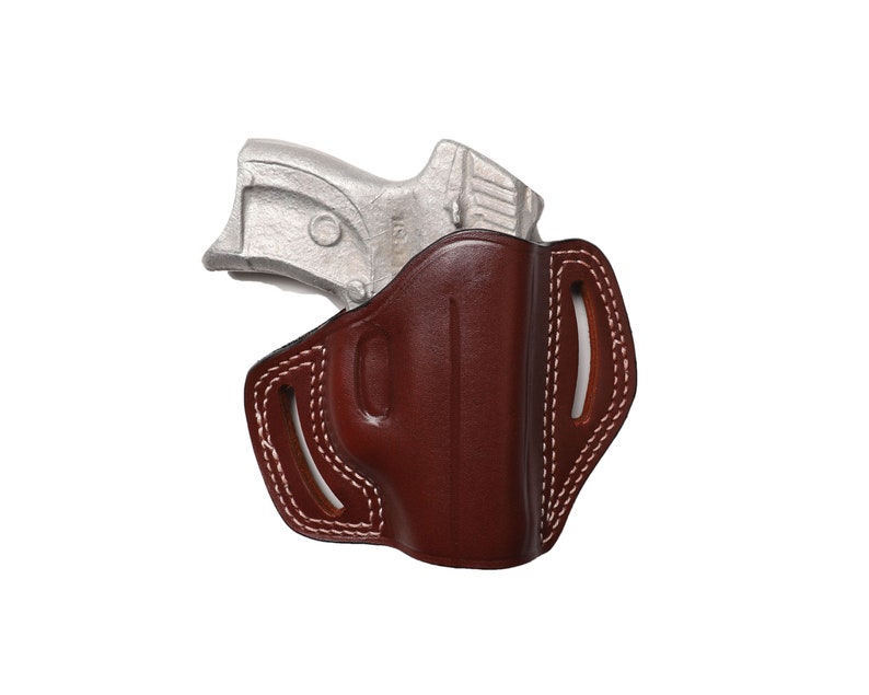 May include: A brown leather holster with white stitching and a silver handgun. The holster has a molded shape and open top, with a belt loop design. The handgun is partially visible, resting inside the holster.