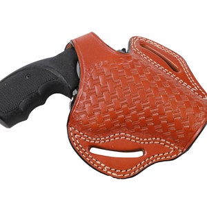 Może przedstawiać: Brązowa skórzana kabura z tkanym wzorem i białymi szwami. Kabura jest przeznaczona do przechowywania broni palnej.