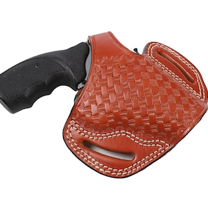 Könnte beinhalten: Ein braunes Lederholster mit einem gewebten Muster und weißen Nähten. Ein schwarzer Revolver ist teilweise in das Holster eingesetzt, wobei der Griff sichtbar ist. Das Holster ist für das Tragen am Gürtel konzipiert.