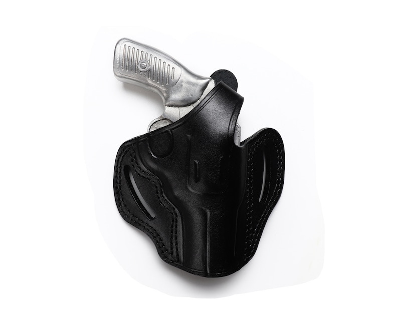 Puede incluir: Una funda de cuero negra para una pistola plateada.
