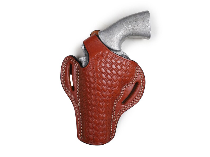 May include: A brown leather holster with a woven pattern and white stitching. The holster is designed to hold a handgun.