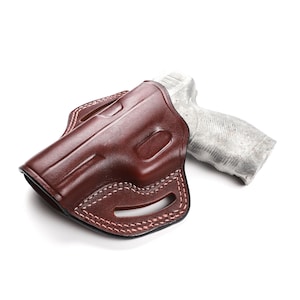 Puede incluir: Una funda de cuero marr&oacute;n con un dise&ntilde;o cosido para una pistola. La funda est&aacute; vac&iacute;a y el arma no es visible.