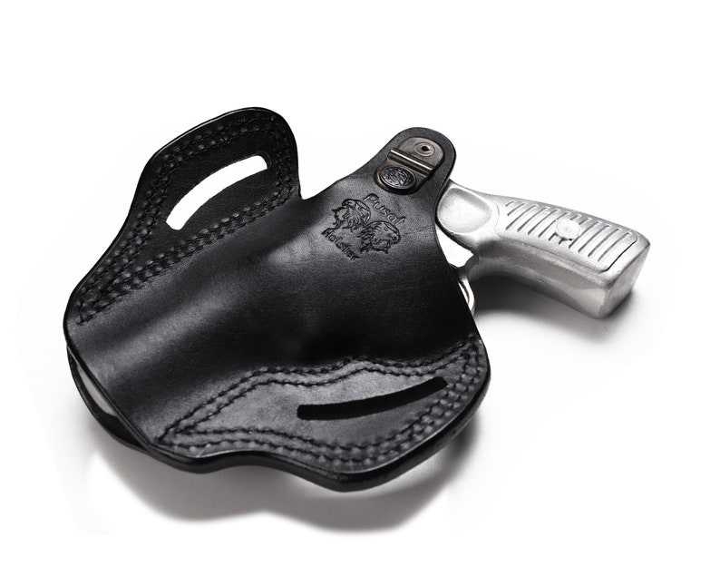 May include: A black leather holster with a silver revolver inside. The holster has a stitched design and a belt loop.
