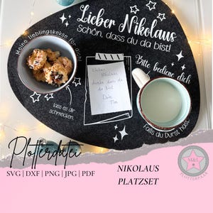 Peut inclure: Un dessous de plat en feutre gris avec un contour blanc d'une tasse, d'une assiette et d'une note. Le dessous de plat porte le texte "Lieber Nikolaus" et "Schön, dass du da bist!" en blanc. Le texte "Bitte bediene dich" est également en blanc. Le dessous de plat est décoré d'étoiles blanches.