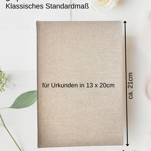 May include: A beige fabric-covered album with the text "Stammbuch" and "Klassisches Standardma&szlig;" in black. The album is approximately 14 cm wide and 21 cm tall. The text "f&uuml;r Urkunden in 13 x 20cm" is printed on the front of the album.
