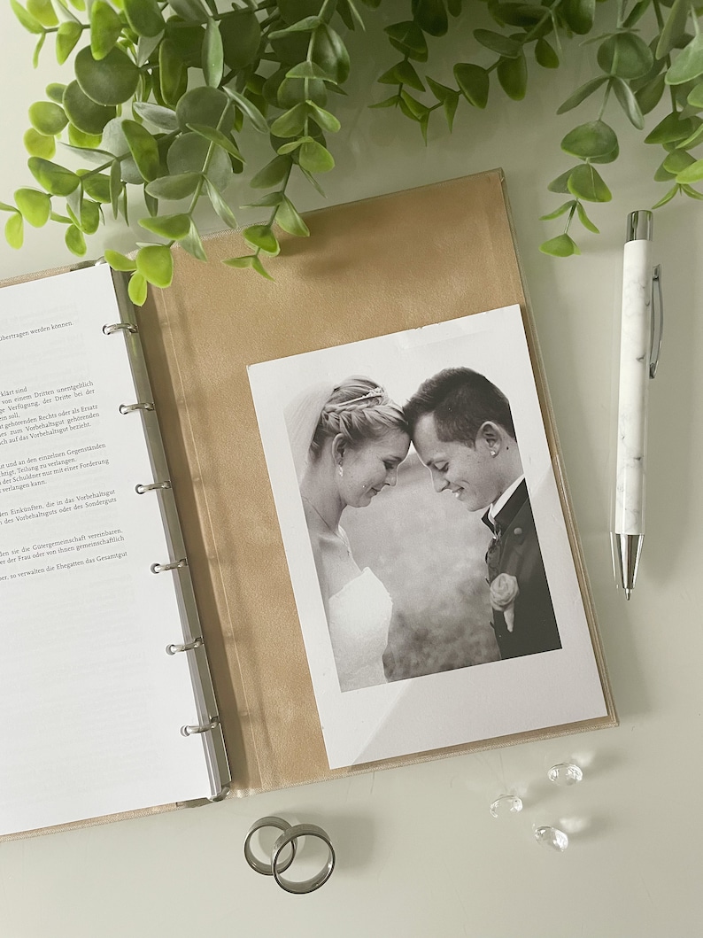 May include: A black and white photograph of a couple looking at each other. The photo is in a brown photo album with a white background.
