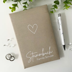 May include: A beige linen-covered journal with a white heart and the text "Stammbuch Familie Schulze" on the front.