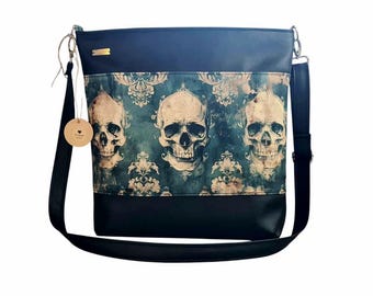Pode incluir: Bolsa de ombro preta com um padrão de caveira e flores. A bolsa tem uma alça longa ajustável.
