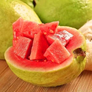 May include: A green guava cut open to reveal bright red, juicy flesh. The guava is sliced into cubes and arranged in the center of the fruit.