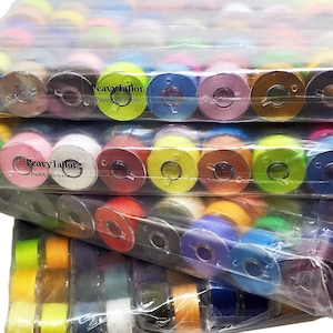 May include: A stack of clear plastic bags filled with colorful spools of thread. The spools are labeled "Peavy Tailor" and "PeavyTailor.com".