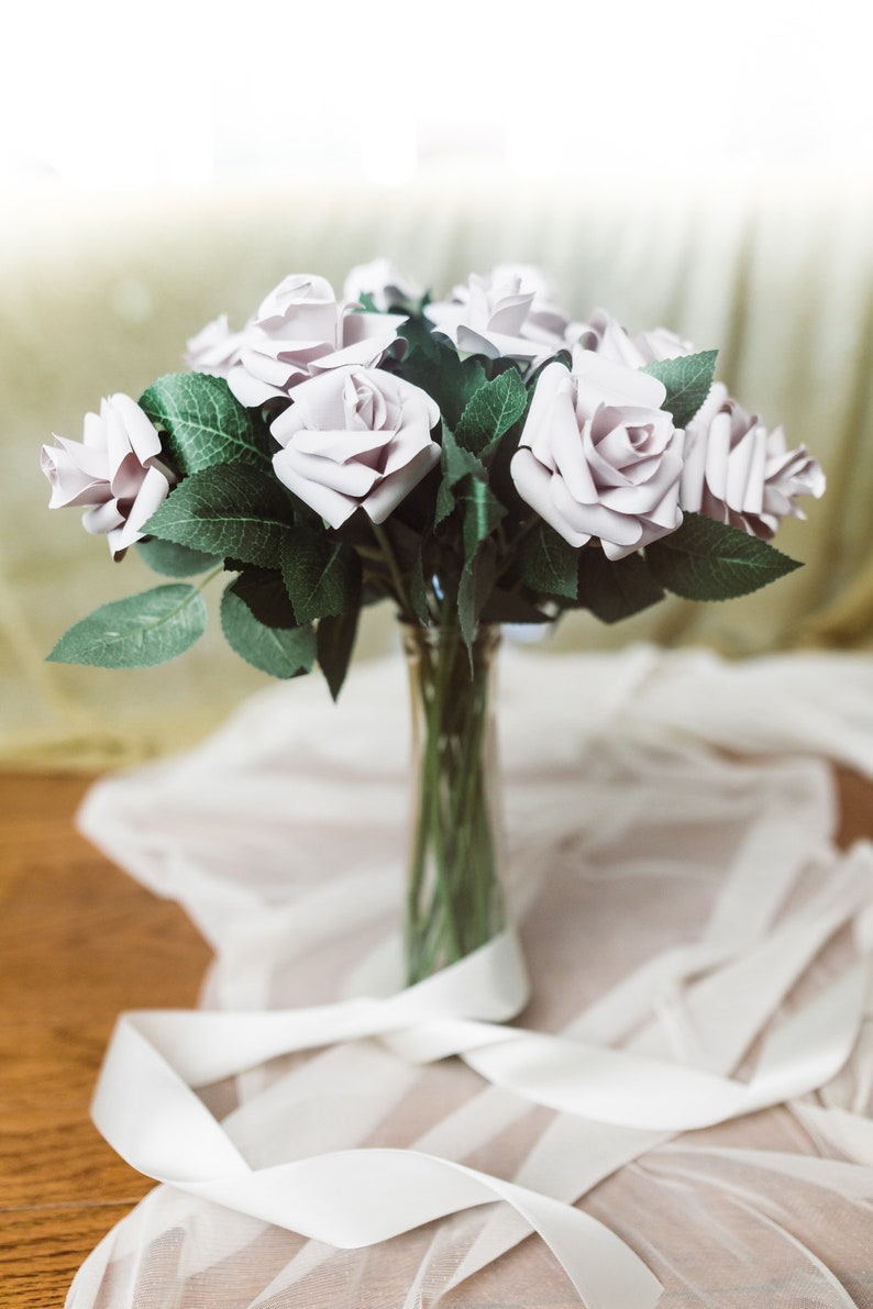 A paper rose made from book pages from a classic favorite novel. The rose is attached to a realistic rose stem with rose leaves.