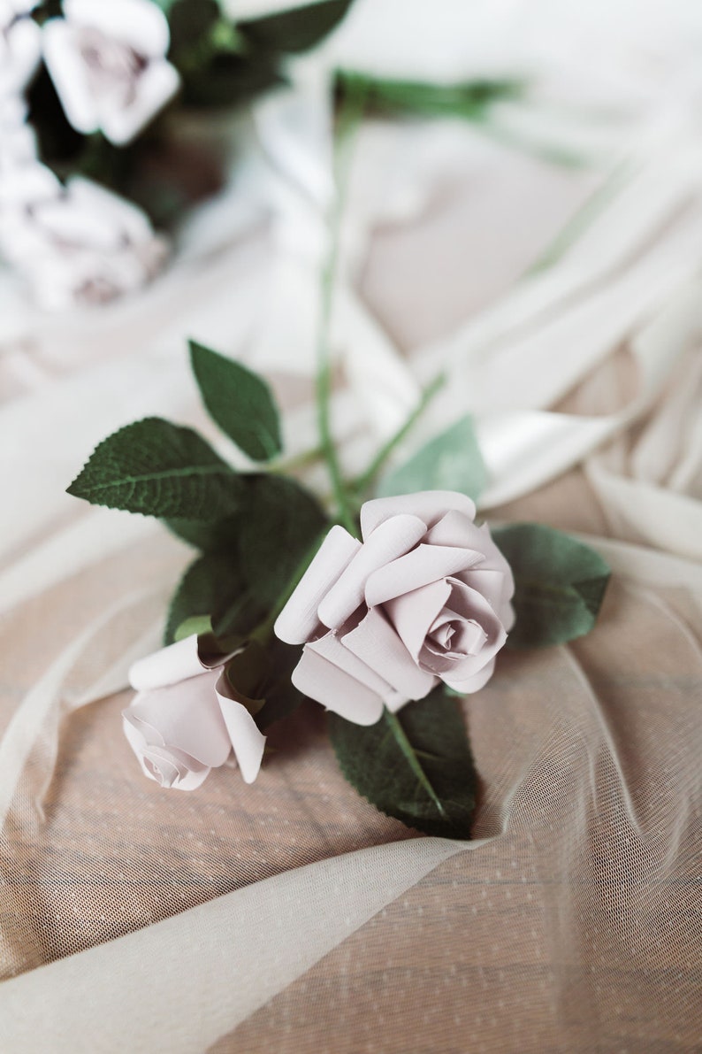 A paper rose made from book pages from a classic favorite novel. The rose is attached to a realistic rose stem with rose leaves.