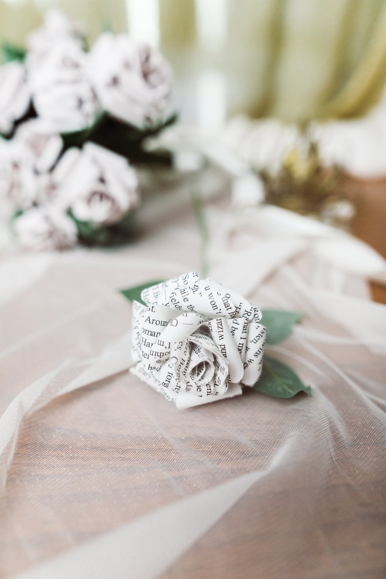 A paper rose made from book pages from a classic favorite novel. The rose is attached to a realistic rose stem with rose leaves.