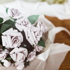 A paper rose made from book pages from a classic favorite novel. The rose is attached to a realistic rose stem with rose leaves.