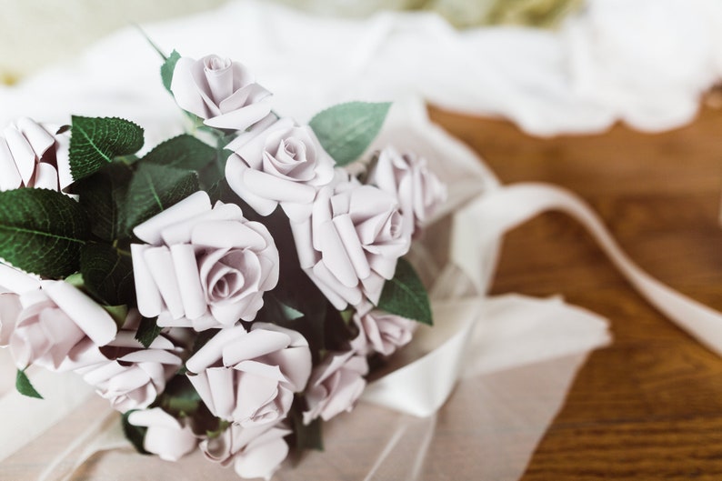 A paper rose made from book pages from a classic favorite novel. The rose is attached to a realistic rose stem with rose leaves.