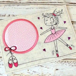 May include: A white felt craft with a pink circle in the center, a pink ballerina with a pink tutu, and pink ballet shoes. The circle has a pink and white polka dot pattern.