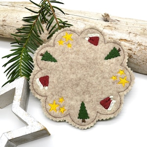 Peut inclure: Une décoration de Noël en feutre beige avec des arbres verts, des bonnets de Père Noël rouges et des étoiles jaunes brodés.