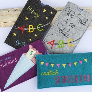 May include: Four felt envelopes with different designs for a new school child. The envelopes are purple, gray, teal, and black. The envelopes have embroidered designs with text such as "1+1=2", "ABC", "Viel Spaß in der Schule", "für das Schulkind", and "endlich SCHULKIND".