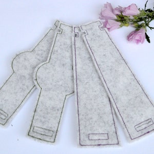 May include: Four white felt fabric bottle covers with green and purple stitching. The covers are designed to fit around a bottle and have a rectangular shape with a rounded top.