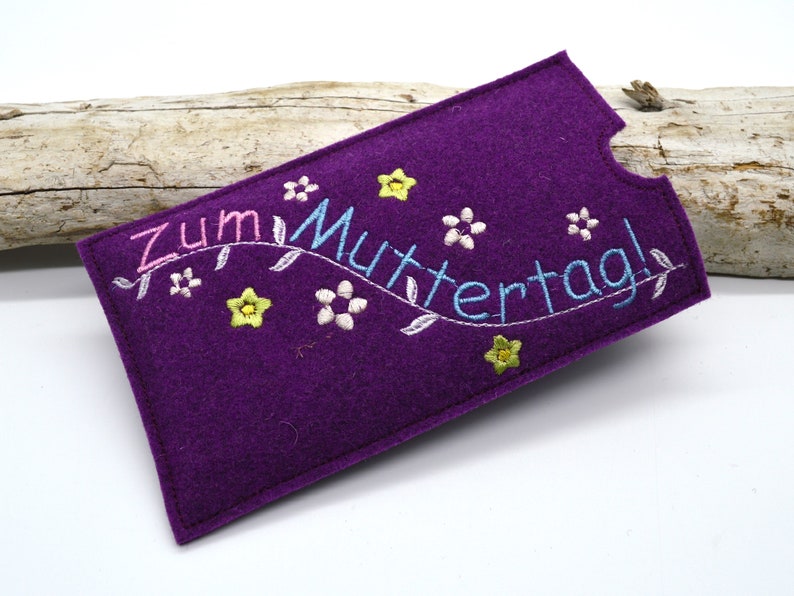 May include: Purple felt phone case with embroidered flowers and the text "Zum Muttertag!" in pink, blue, and yellow thread.