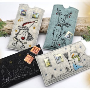 May include: Four felt Christmas gift envelopes with embroidered designs. The envelopes are decorated with a Santa Claus, a reindeer, a snowman, and a winter village. Each envelope has a slot for money and a number on the front. The envelopes are on a wooden surface.