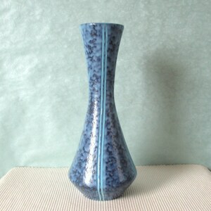 Könnte beinhalten: Eine blaue Keramikvase mit gesprenkelter Glasur und zwei dünnen weißen Streifen, die vertikal über die Vorderseite verlaufen.