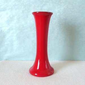 Può includere: Un vaso in ceramica rosso vivo con una base svasata e un collo stretto.