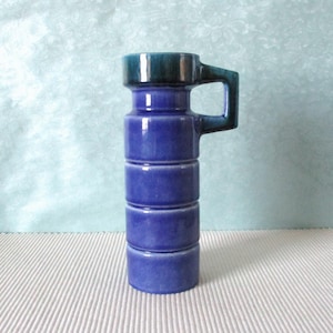 Könnte beinhalten: Eine blaue und grüne Keramikvase mit Henkel. Die Vase hat ein strukturiertes, geripptes Design.