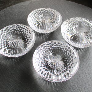 Puede incluir: Cuatro candelabros de vidrio transparente con un diseño texturizado en relieve. Los candelabros tienen una abertura central para una vela.