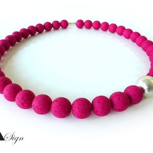 Könnte beinhalten: Eine pinkfarbene Lava-Perlenkette mit einem silbernen Perlenakzent.