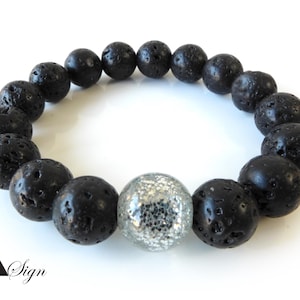 Könnte beinhalten: Ein Armband aus schwarzen Lavasteinen mit einem silbernen Glitzer-Akzentperle.
