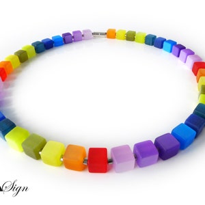 Può includere: Una collana arcobaleno realizzata con perline quadrate di vetro. La collana è realizzata con una varietà di colori, tra cui rosso, arancione, giallo, verde, blu, indaco e viola.