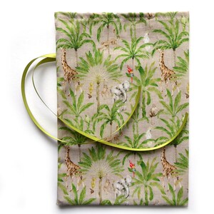 Könnte beinhalten: Eine beige Stofftasche mit einem grünen und braunen Dschungel-Druck mit Giraffen, Palmen und Papageien. Die Tasche hat ein grünes Band darum gebunden.